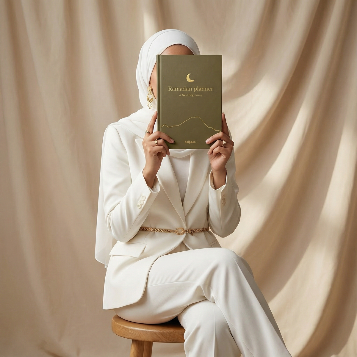A woman in white holding the Qalbeen Ramadan Planner